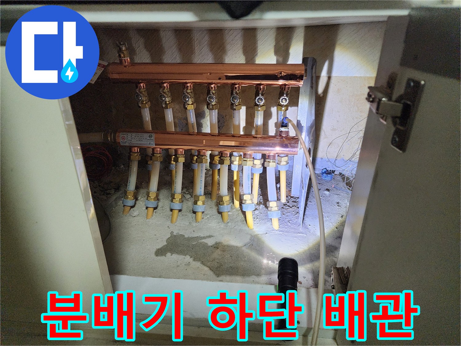 싱크대 아래 분배기와 연결된 여러 개의 배관 라인이 보이는 사진입니다.
