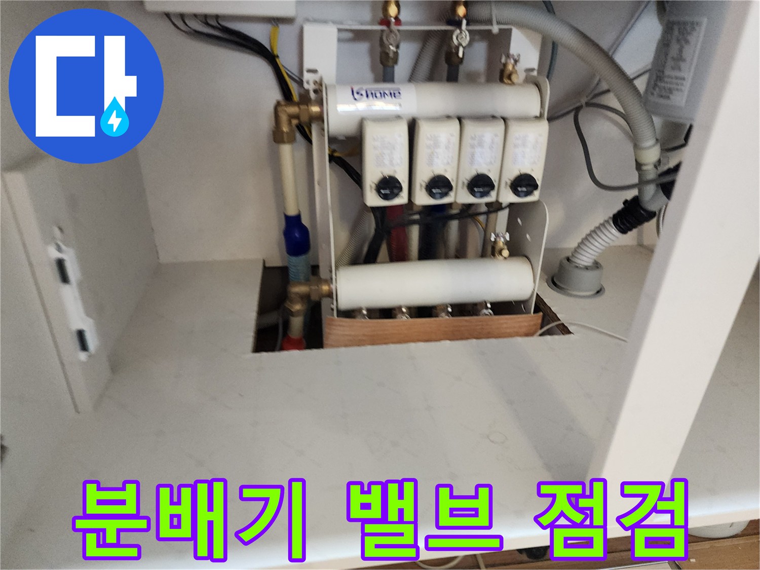 싱크대 아래 설치된 수도 분배기와 연결 호스들