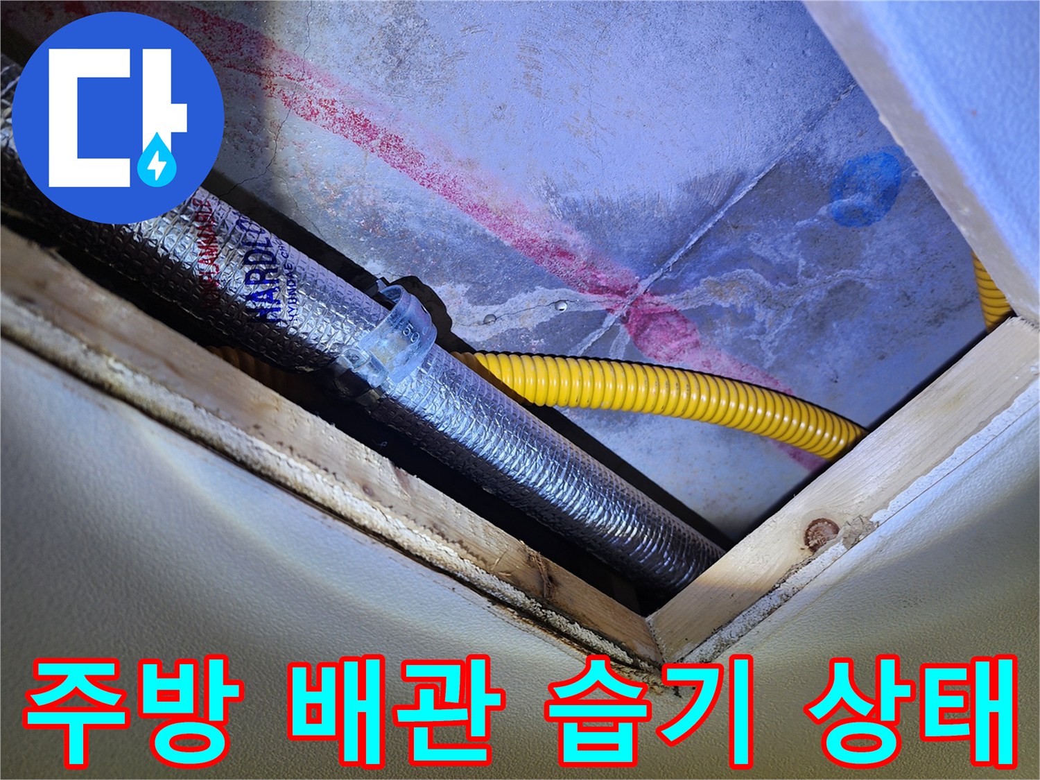 싱크대 하부 공간의 노란색 배관과 은색 보온재 주변에 나타난 젖은 흔적