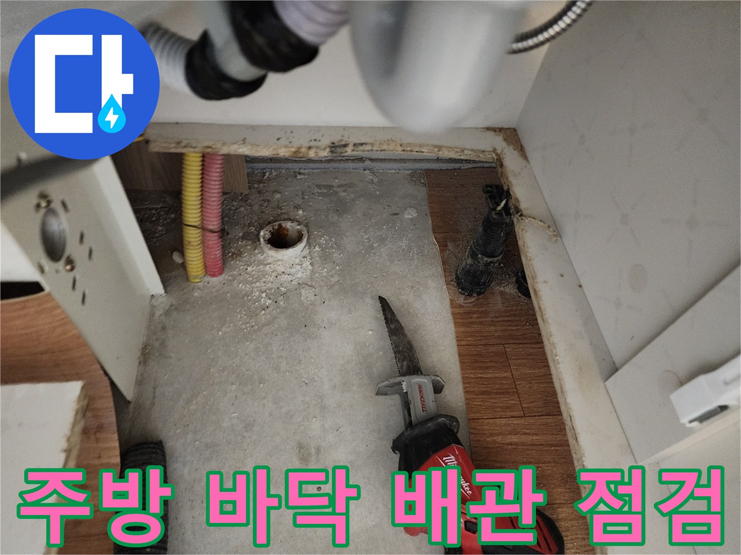 싱크대 하부 굴착 부위에서 보이는 노출된 배관과 작업 도구