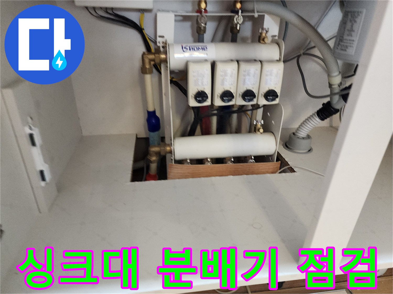 주방 싱크대 하부장의 배관 분배기와 연결 부위 모습입니다.