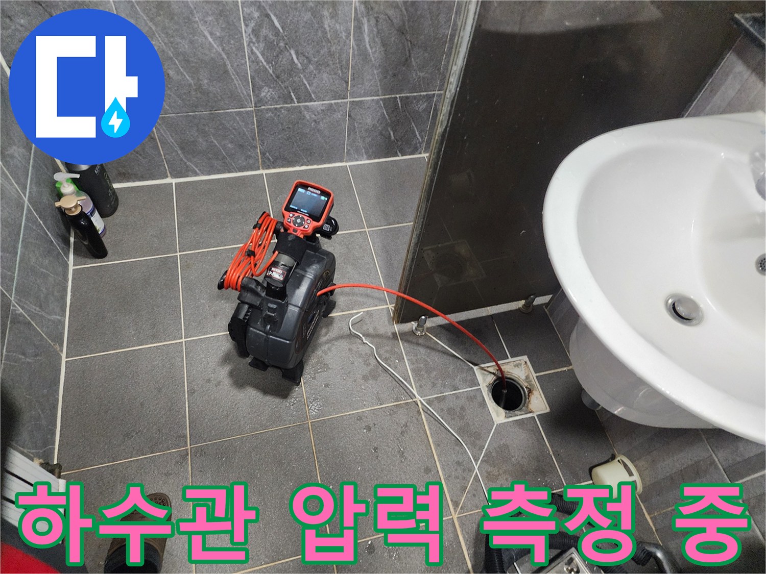 바닥 배수구 근처에 설치된 배관 압력 테스트 장비와 호스