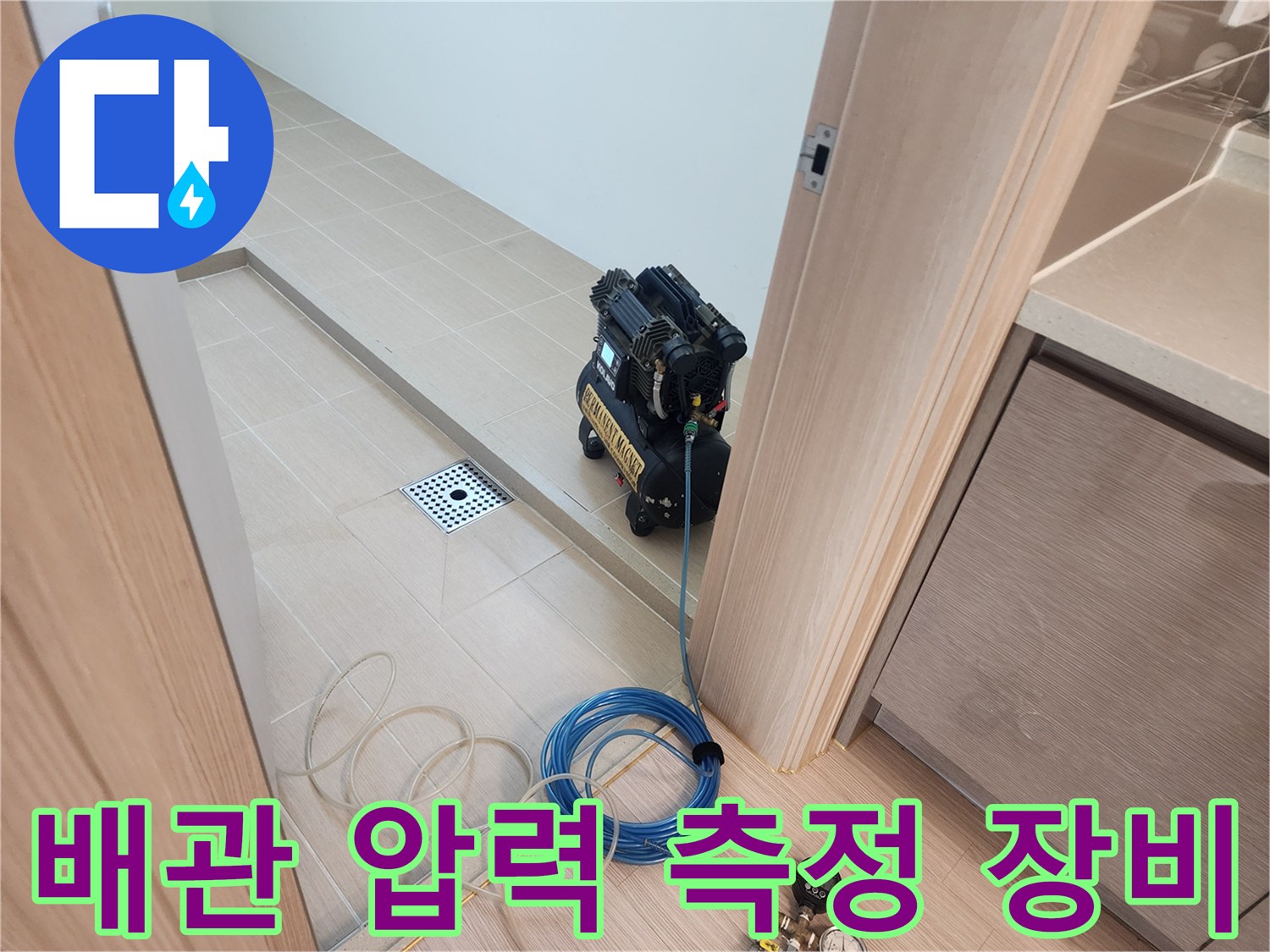화장실 바닥 배수구 옆에 세팅된 공압 테스트용 에어 컴프레서와 호스