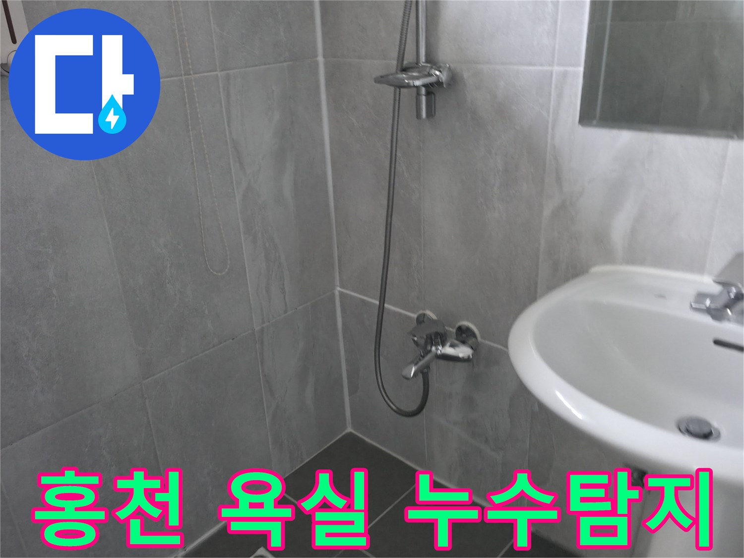 회색 타일로 마감된 깨끗한 욕실 내부-샤워기와 세면대가 보이는 모습