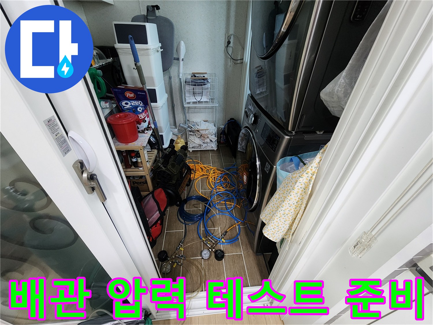 세탁실 바닥에 놓인 파란색 호스와 수압 측정용 게이지