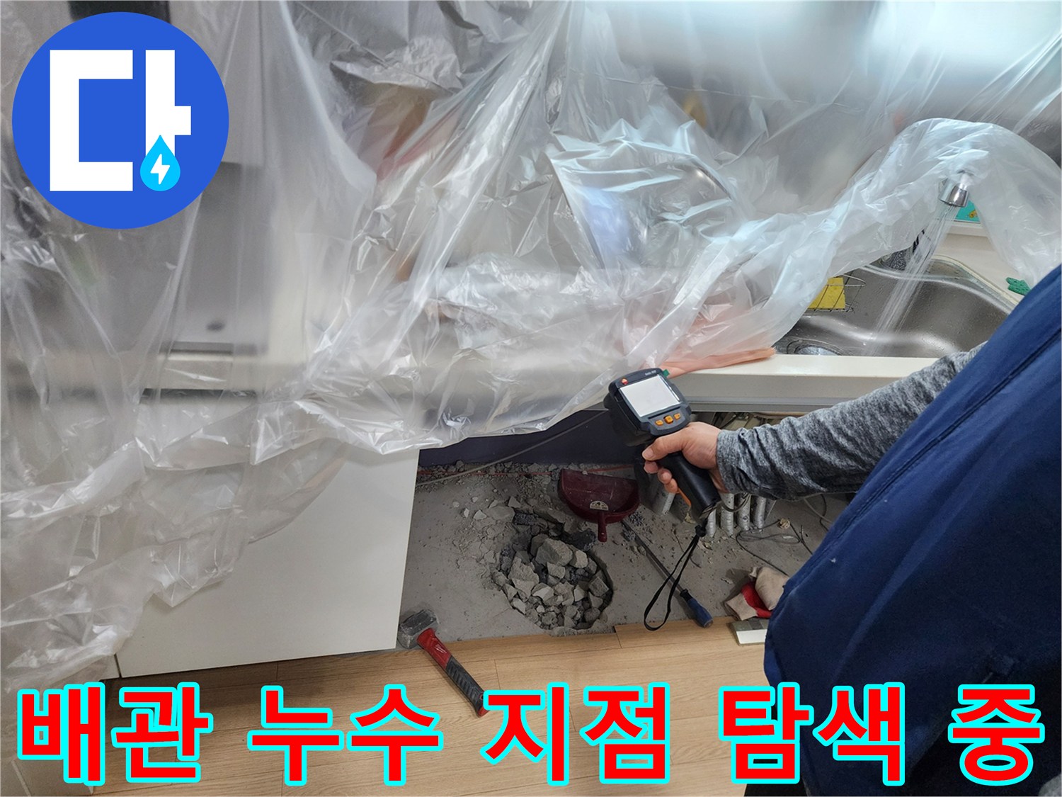 싱크대 아래 공간에서 배관 누수를 찾기 위해 장비를 운용하는 엔지니어
