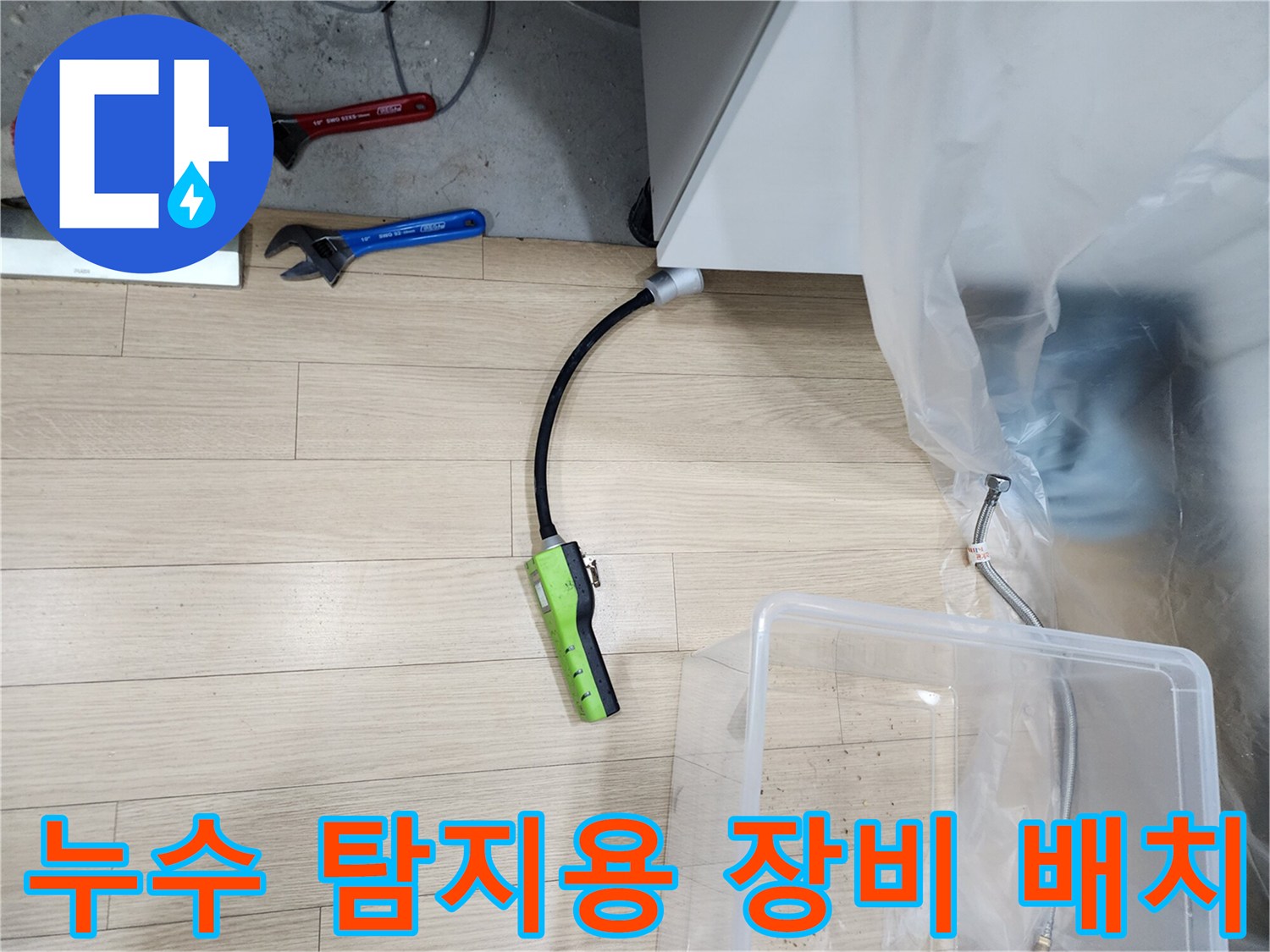 싱크대 아래 보양된 공간에 놓인 가스 탐지기와 작업 도구들