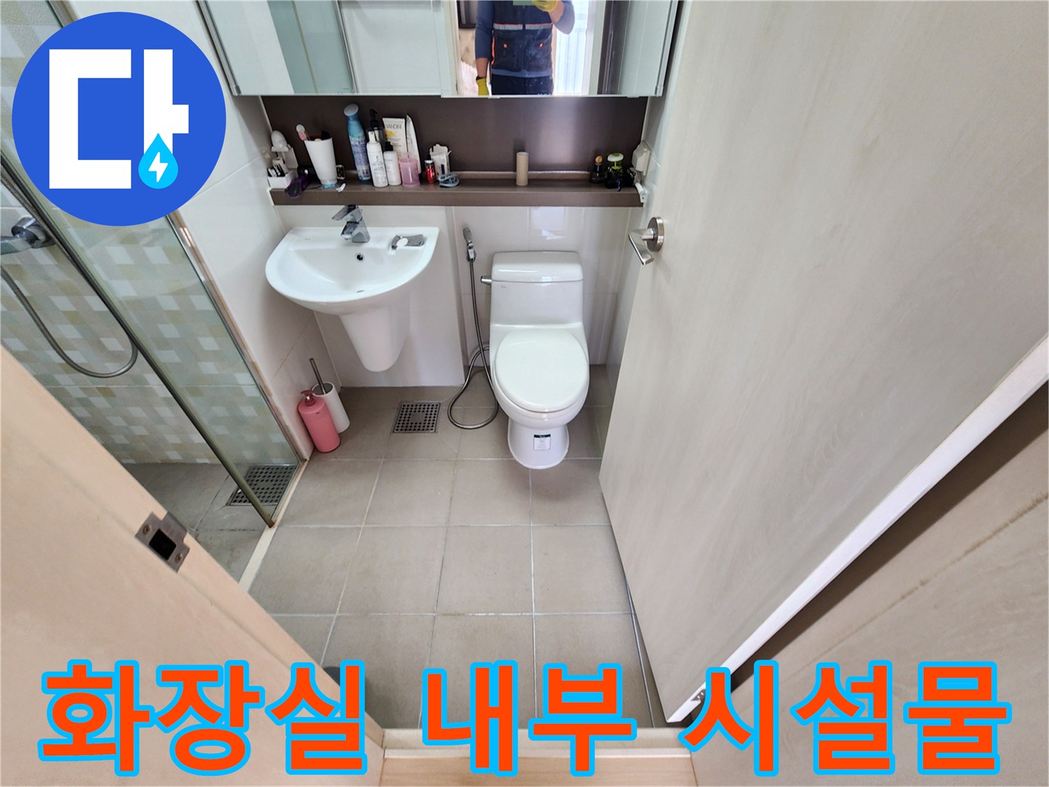 세면대와 양변기가 설치된 화장실 내부의 전체적인 모습입니다.