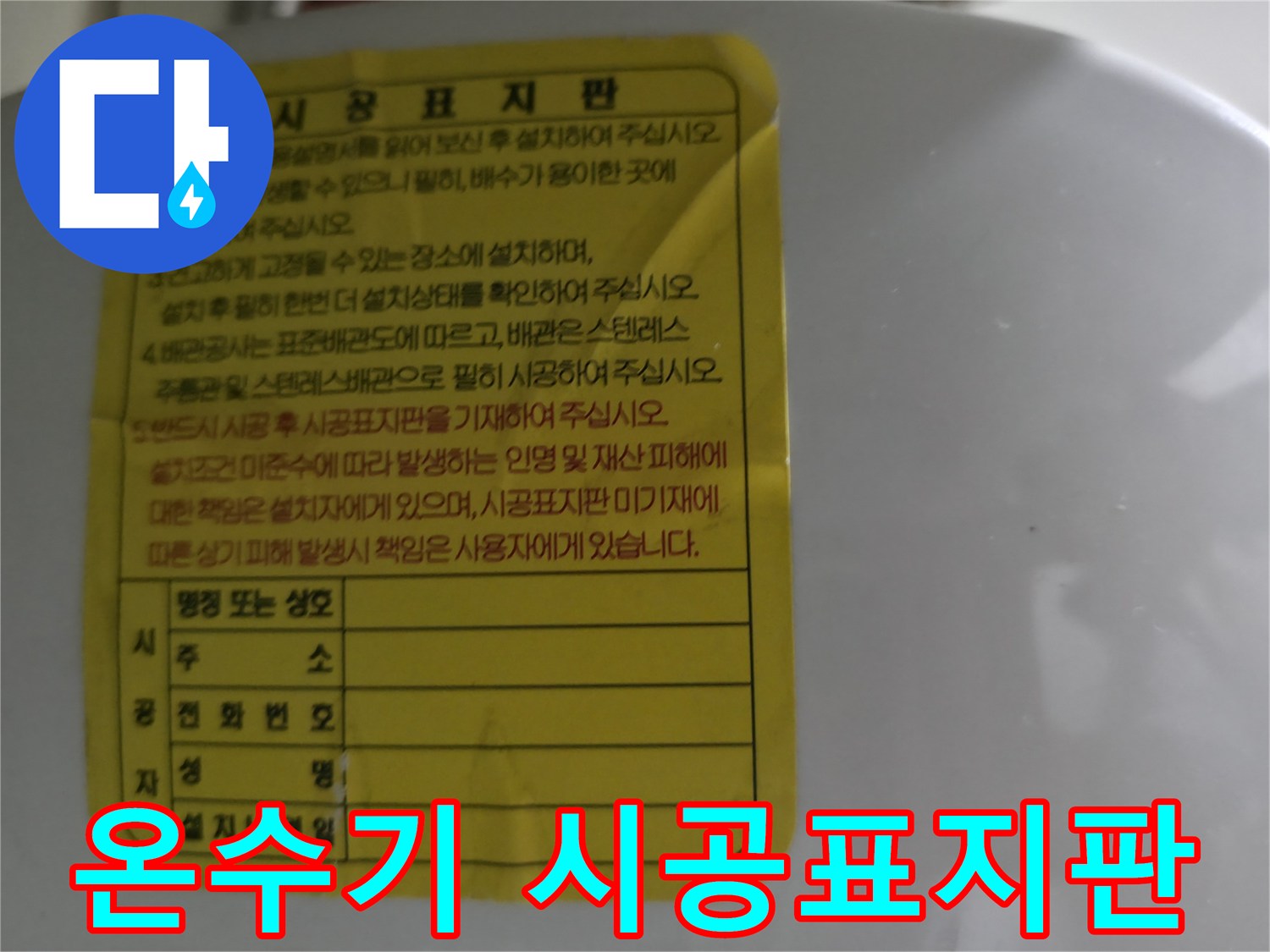소형 전기 온수기에 부착된 설치 정보가 담긴 시공표지판 사진입니다.