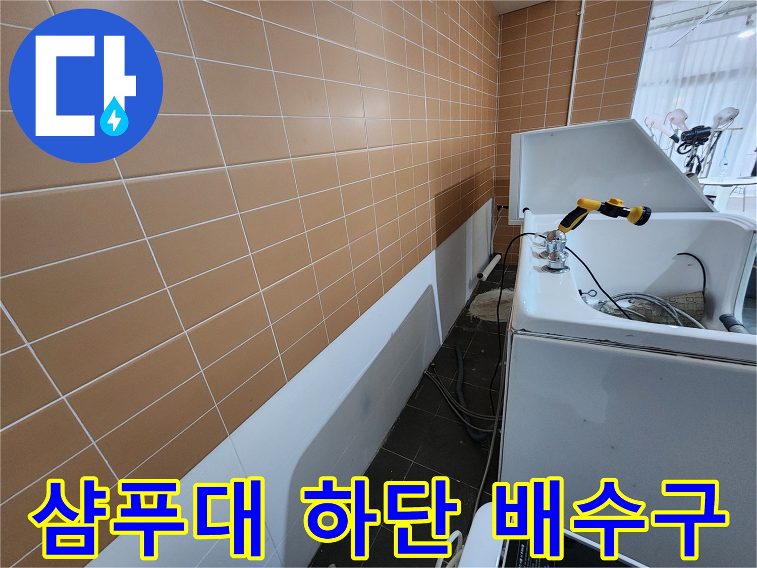 미용실 샴푸대 하부-배수 호스 및 벽면 타일 모습