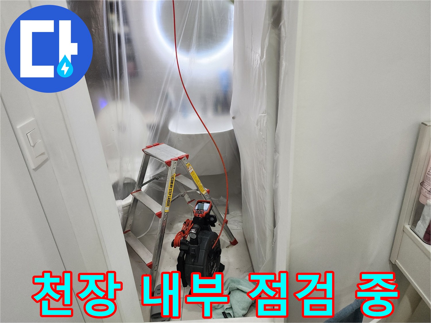 비닐로 보양된 작업 공간에서 내시경 장비를 사용하여 배관을 조사하고 있습니다.
