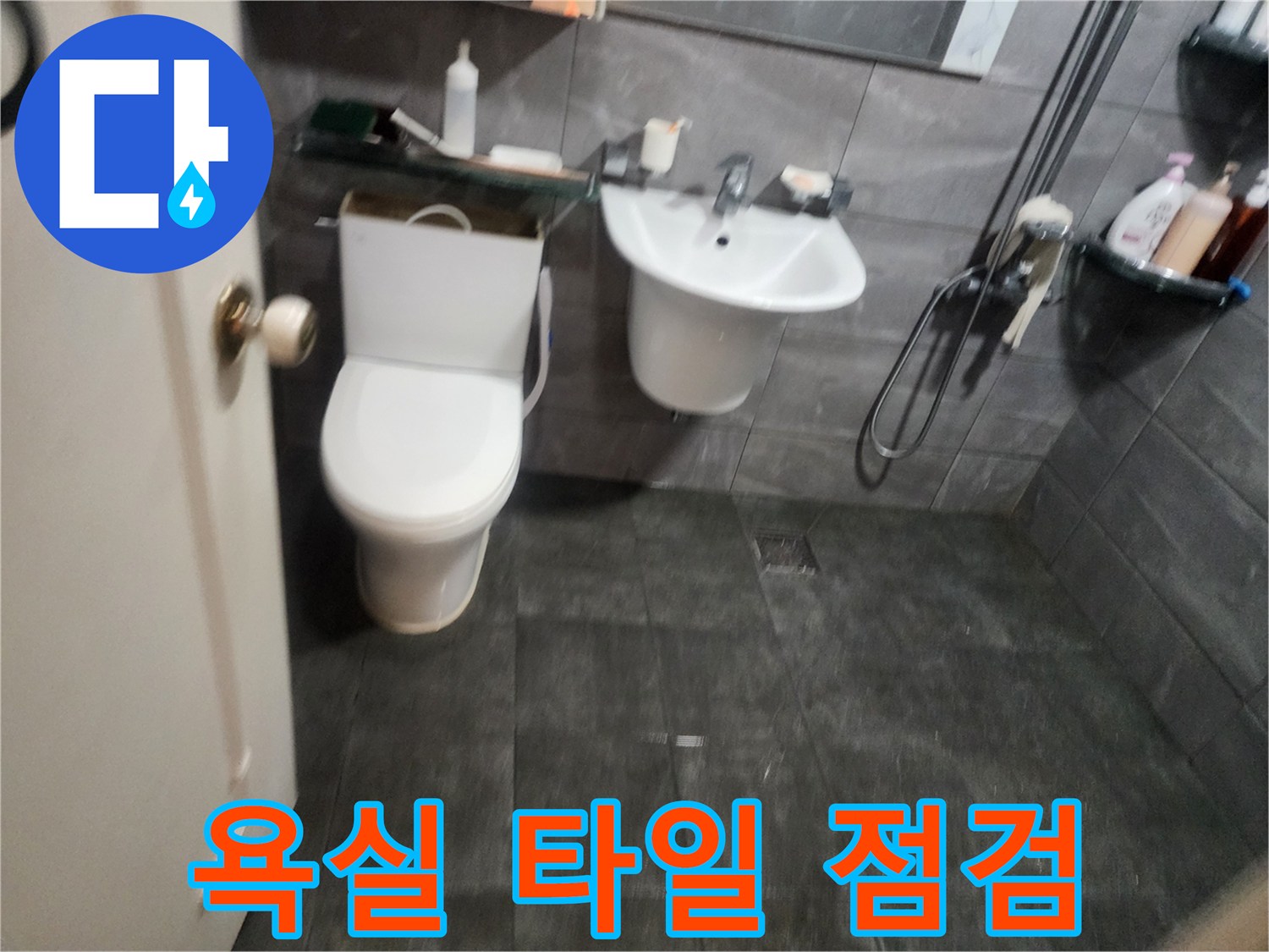 어두운 색상의 욕실 타일과 세면대 배치 상황