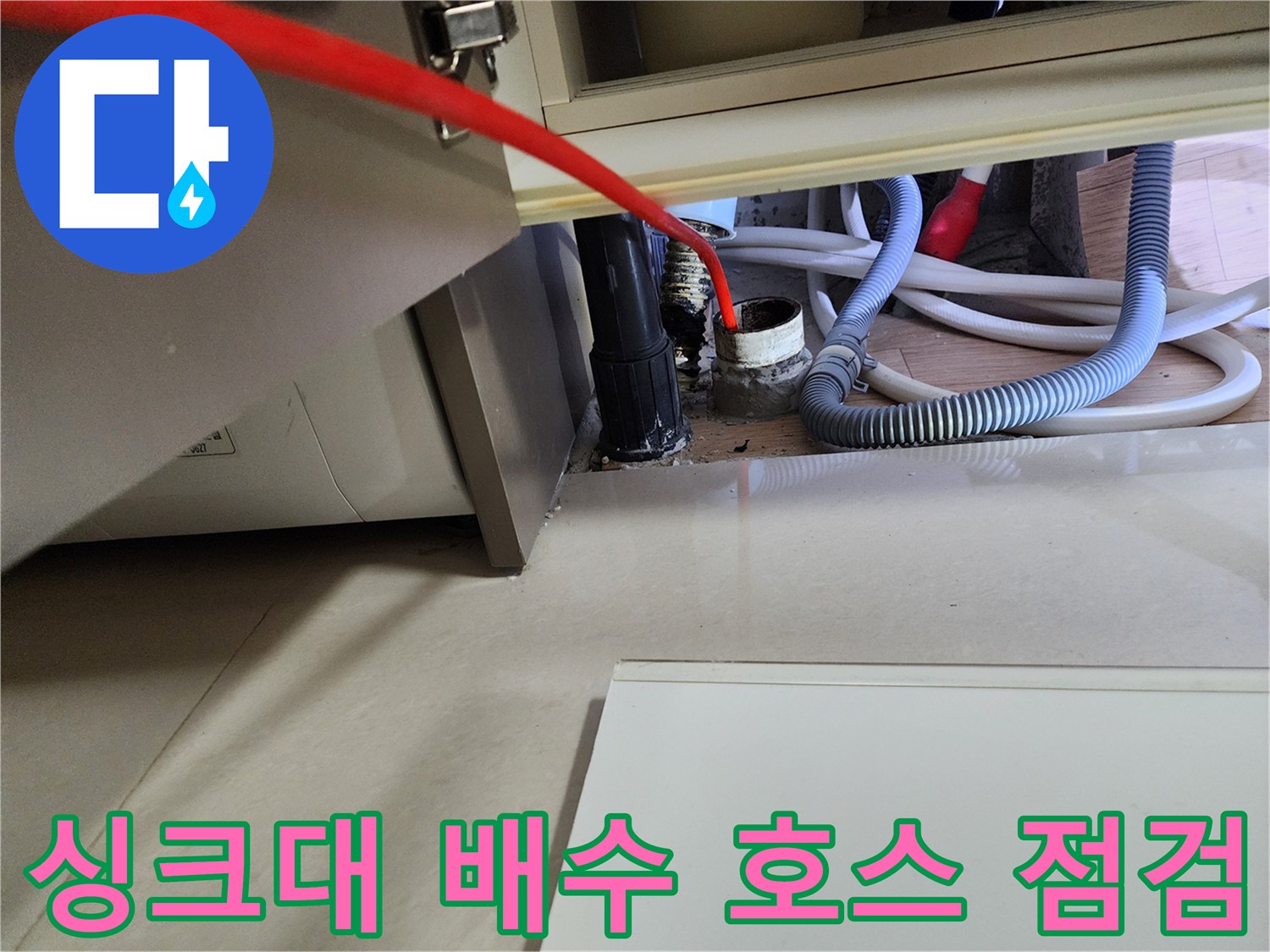 싱크대 아래쪽의 굴곡진 배수 호스와 바닥 배관 연결 부위 모습