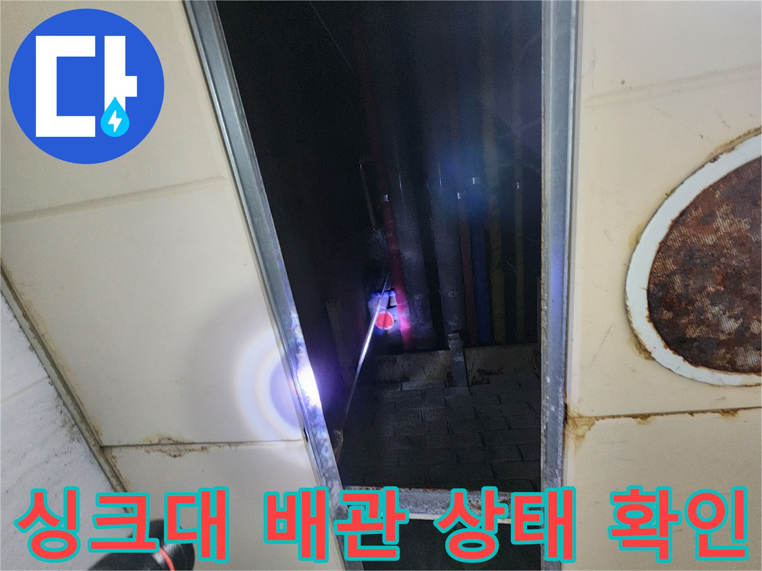 어두운 싱크대 하부 배관 연결 부위의 정밀 진단 장면