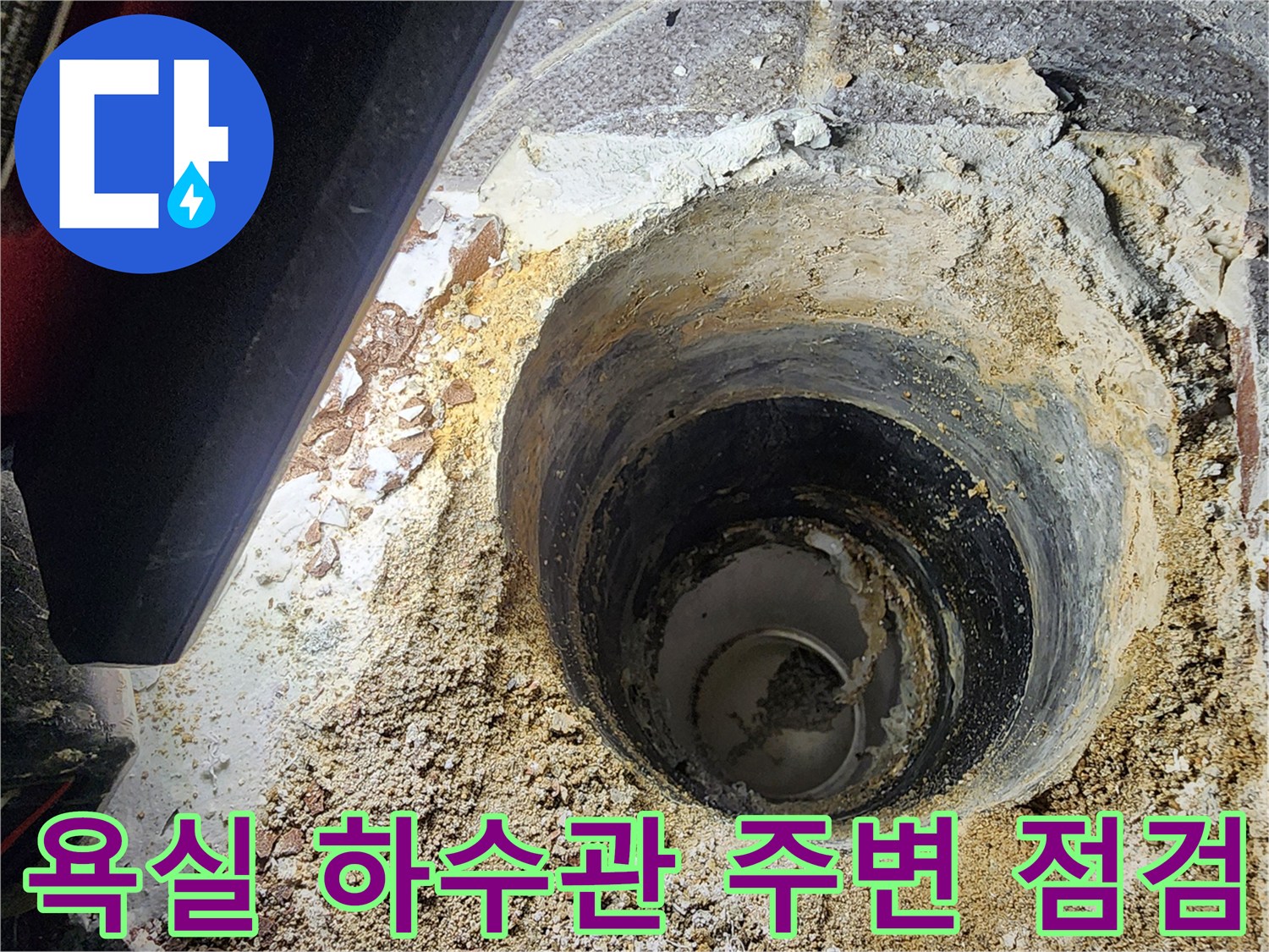 욕실 하수구 배관 주변의 젖은 흔적과 파손된 마감재 상태를 보여주는 사진입니다.