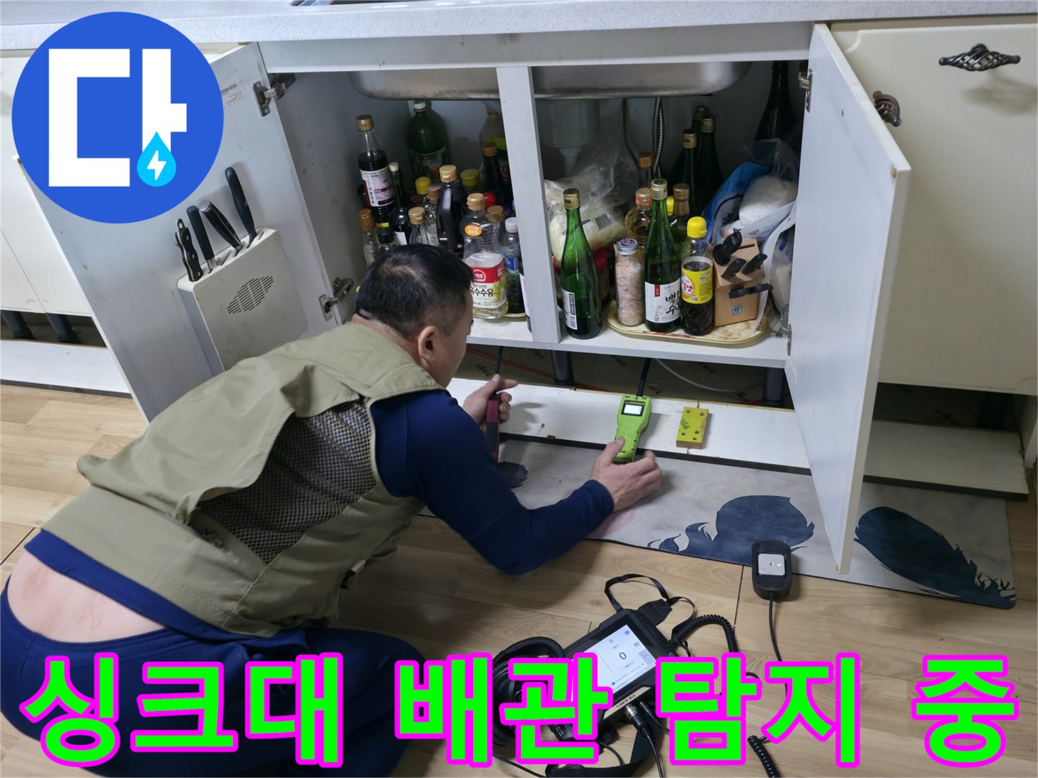 싱크대 하부 공간에서 가스 탐지기를 사용하여 누수를 진단하는 엔지니어의 작업 모습입니다.