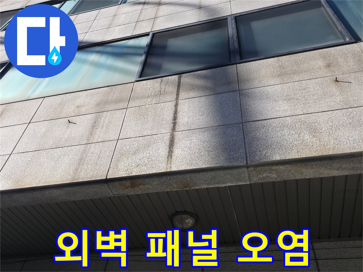 건물 외벽의 석재 마감재에 나타난 짙은 수분 침투 및 변색 흔적