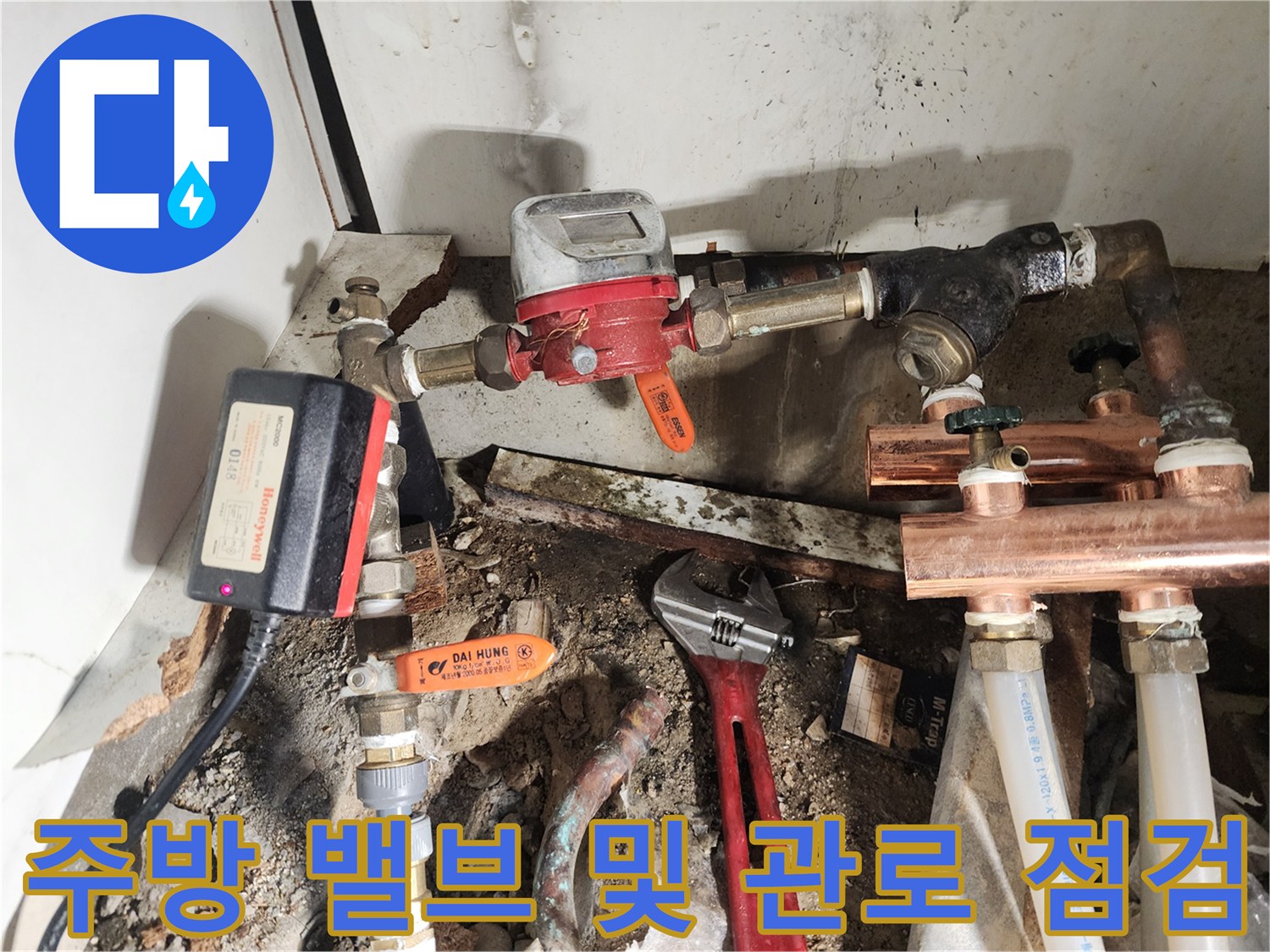 싱크대 하단에 위치한 금속 배관과 붉은색 조절 밸브 모습