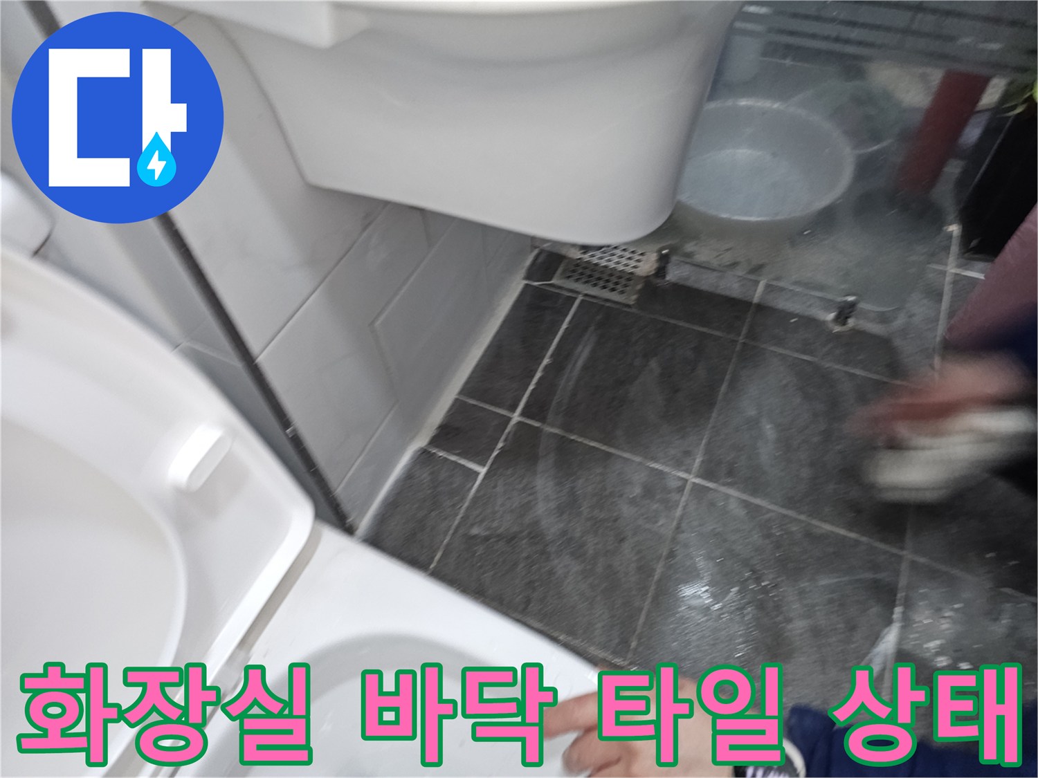 변기 주변-어두운 색상의 욕실 타일과 하단 배관 부근의 모습