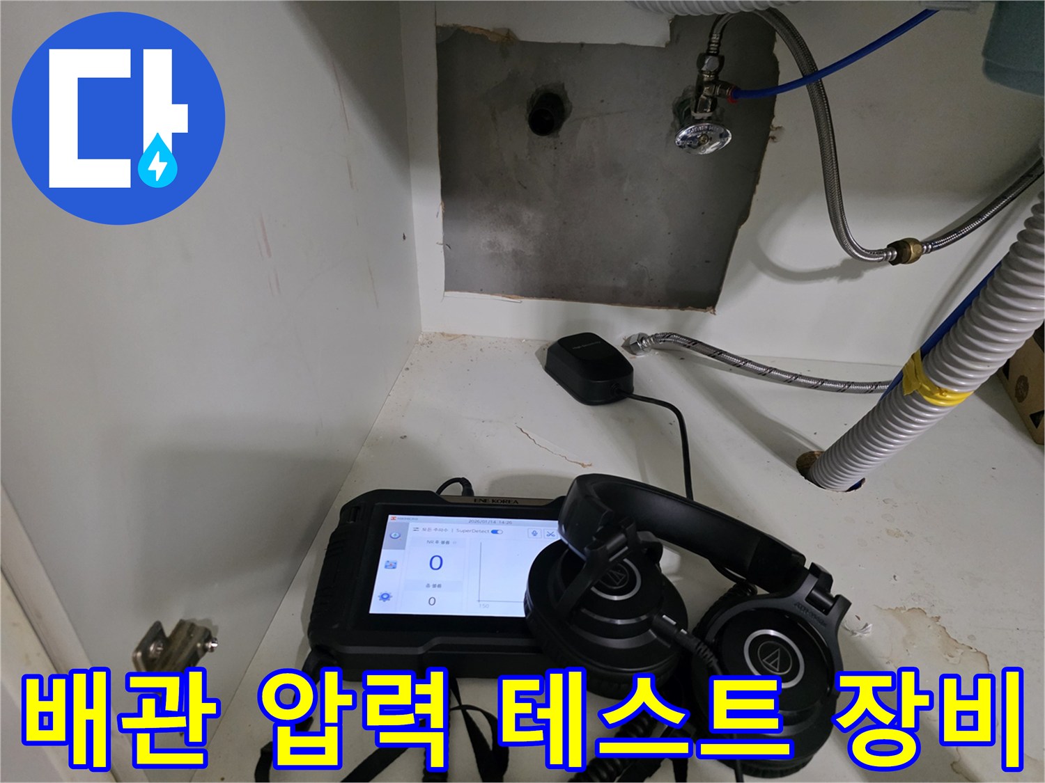 싱크대 하부 배관의 누수 여부를 확인하기 위한 디지털 압력 게이지와 청음 헤드셋 세팅 모습입니다.