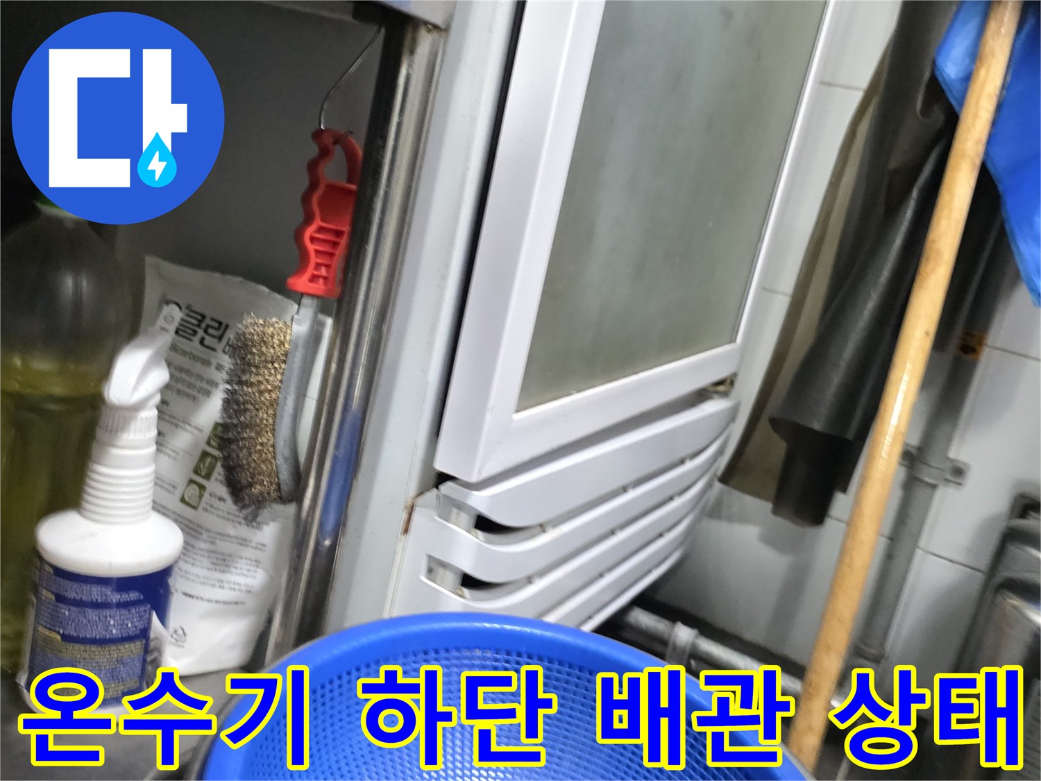 온수기 아래쪽 배관과 주변에 놓인 작업용 자재들의 모습입니다.