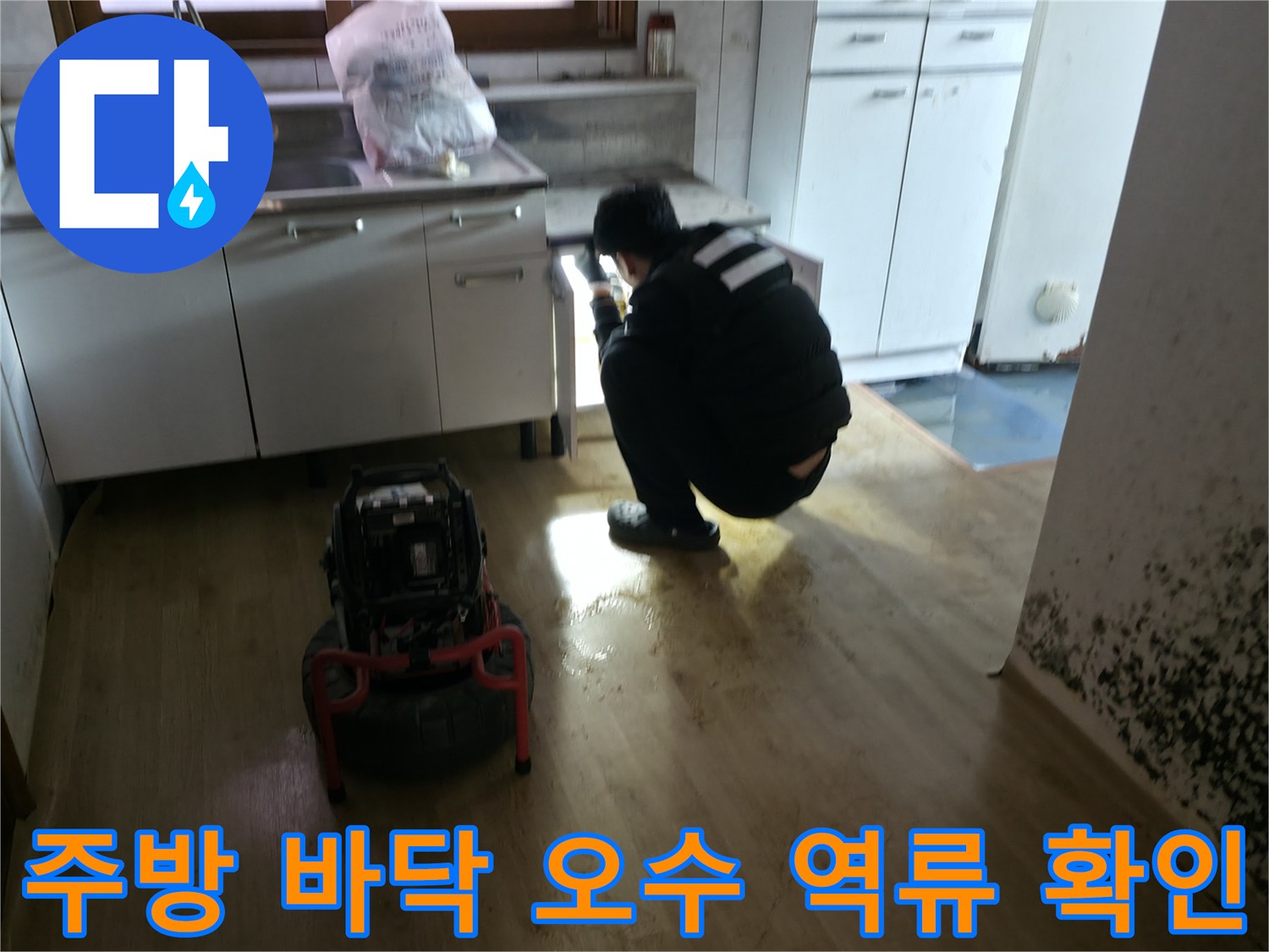 싱크대 밑 배관 부위를 면밀히 살펴보는 엔지니어의 작업 모습