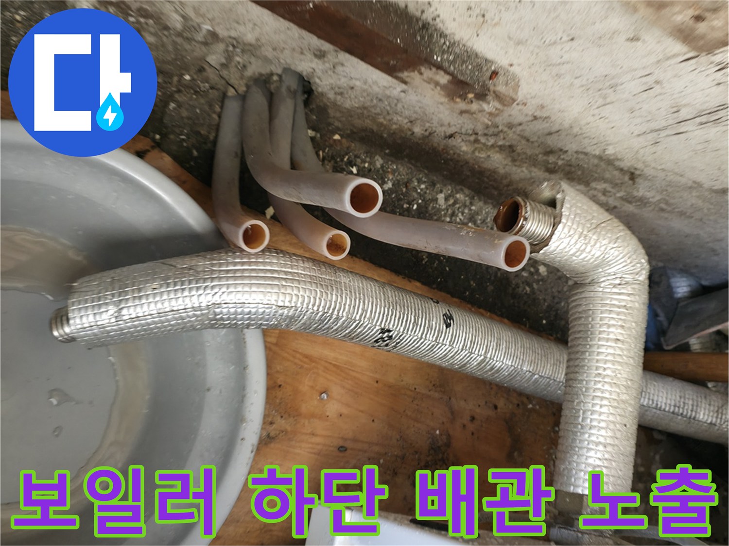 보일러 본체 아래쪽의 은색 보온재 배관과 주황색 분기 배관 상세 모습