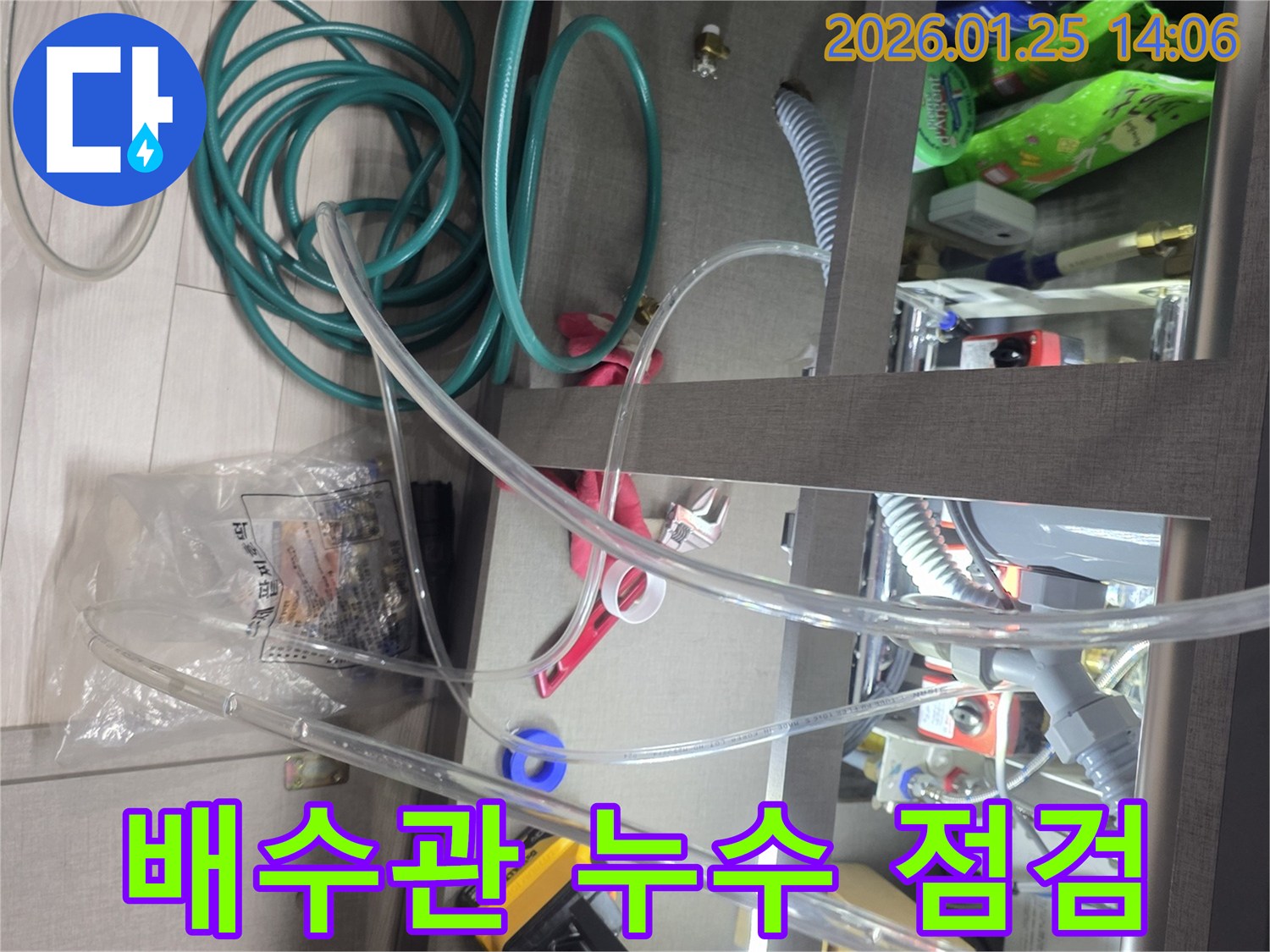 싱크대 하부의 배수관에서 발생한 누수를 점검하는 현장입니다-다양한 호스와 도구를 사용하여-누수 지점을 면밀히 파악합니다.