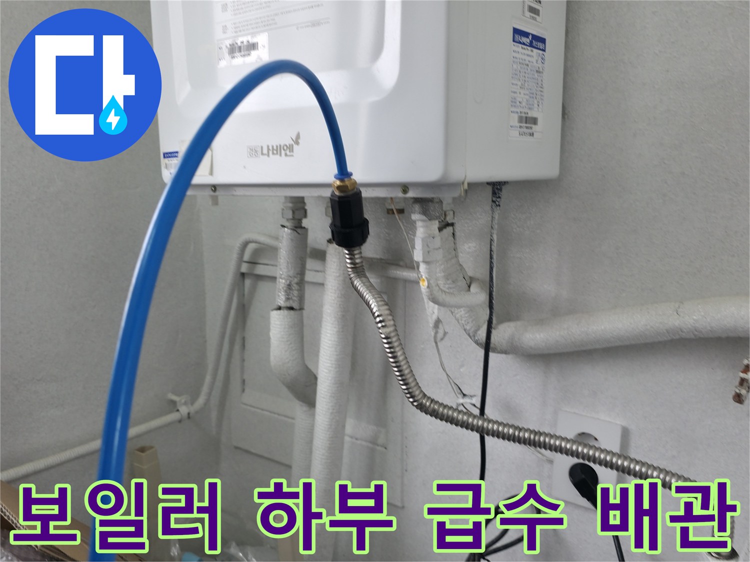하얀색 보일러 기기 아래로 연결된 파란색 호스와 은색 금속 배관