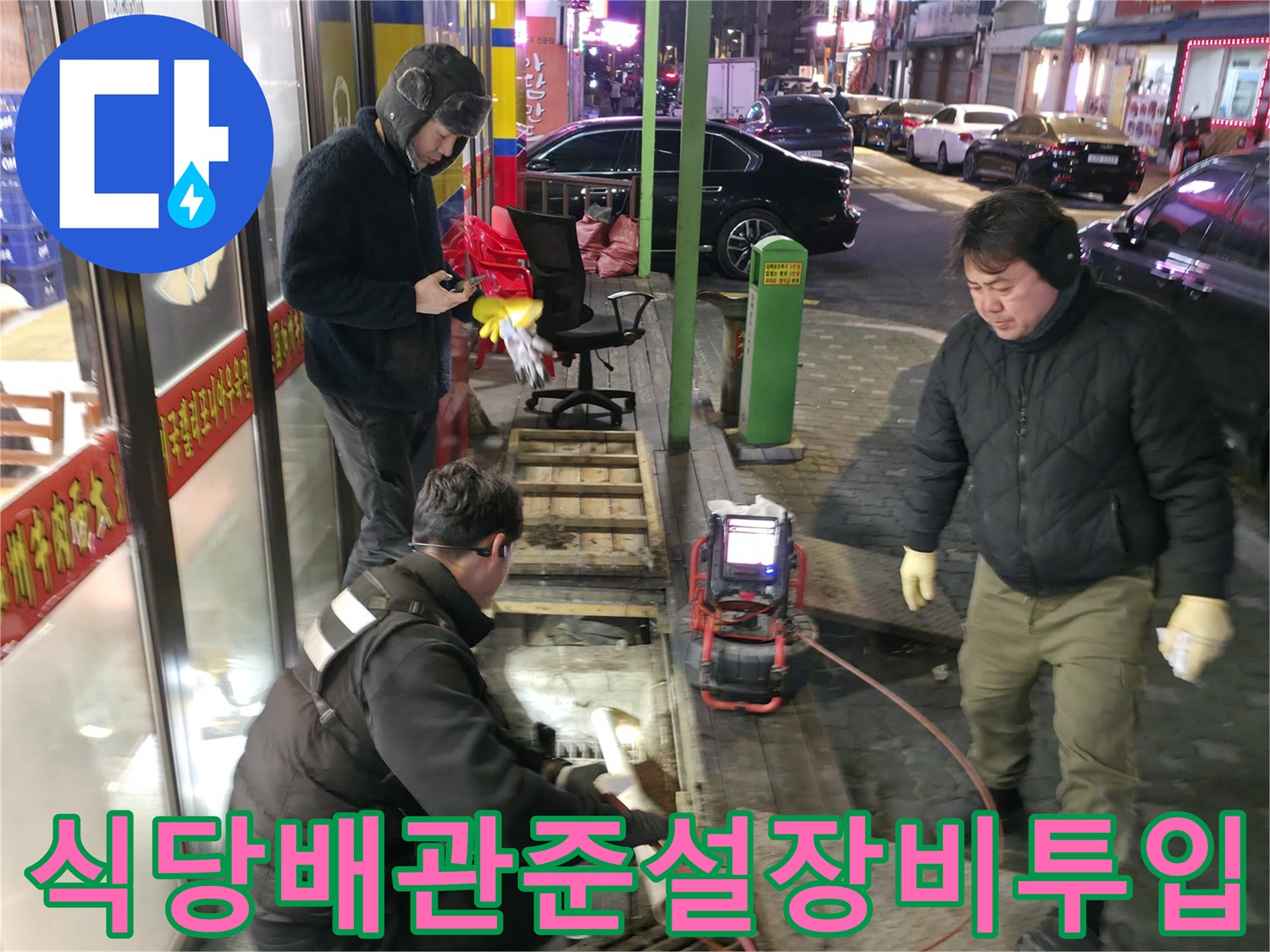 식당 외부에서 고압 세척기와 흡입 장비를 연결하여 배관을 청소하는 모습