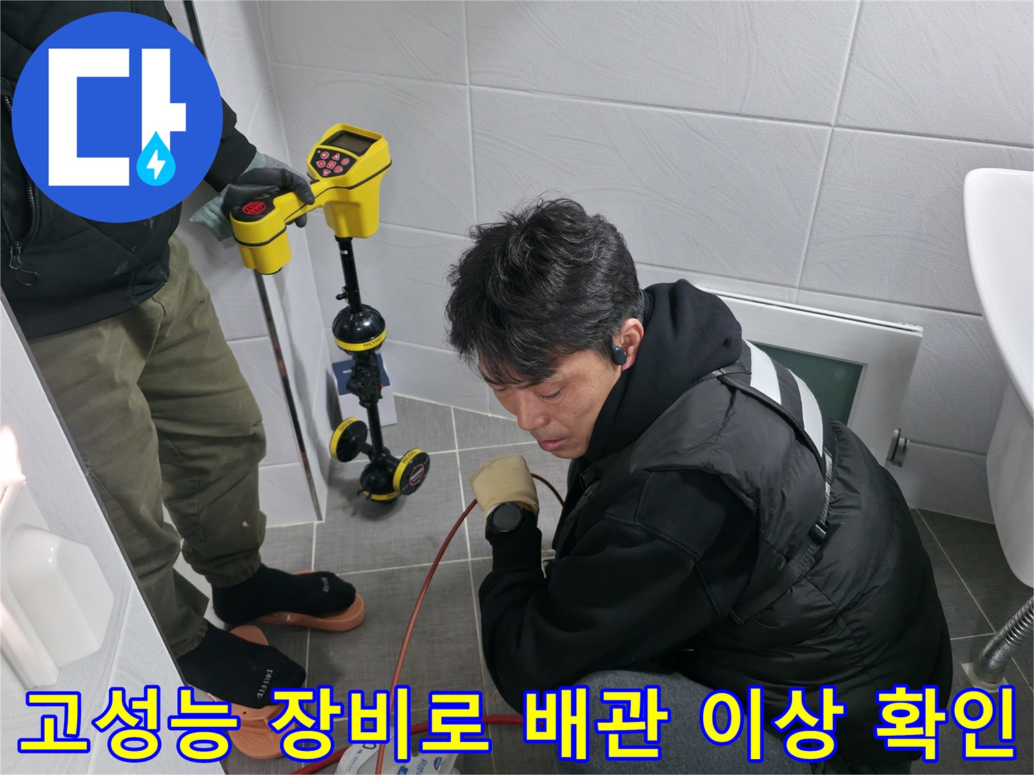 화장실 내부에서 정밀 탐지기를 사용하여 매립된 배관의 상태를 점검하는 모습