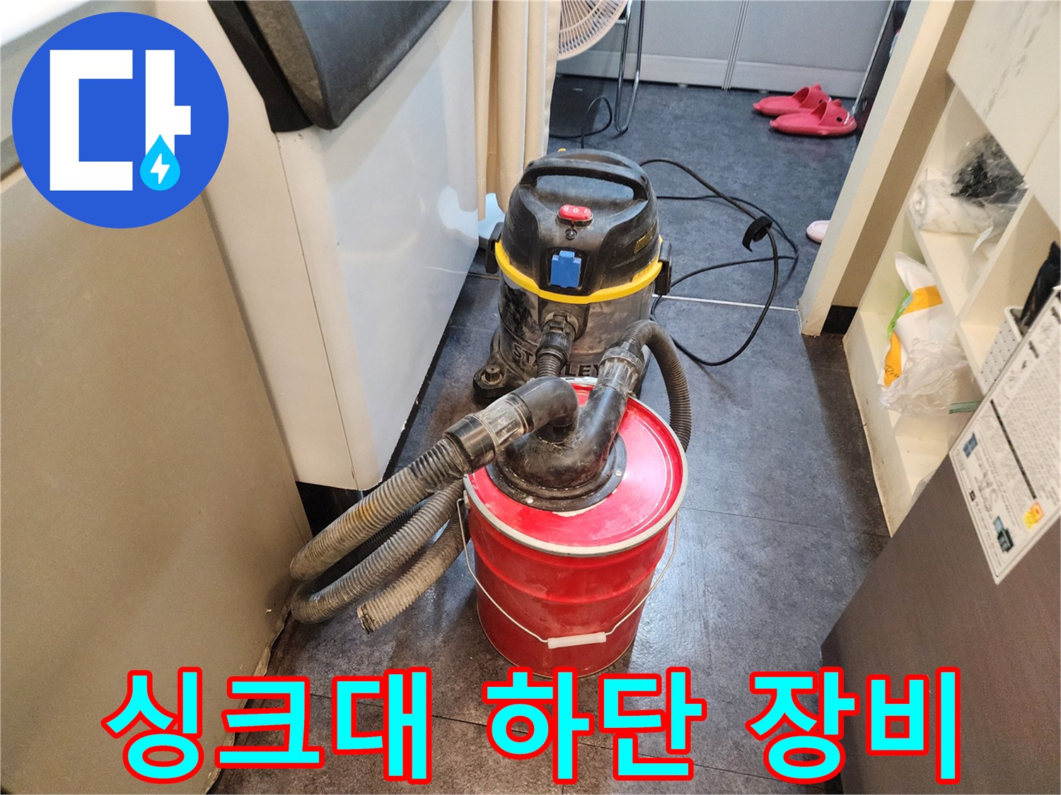 누수 탐지를 위해 싱크대 밑 공간에 배치된 청소용 집진기와 붉은 통