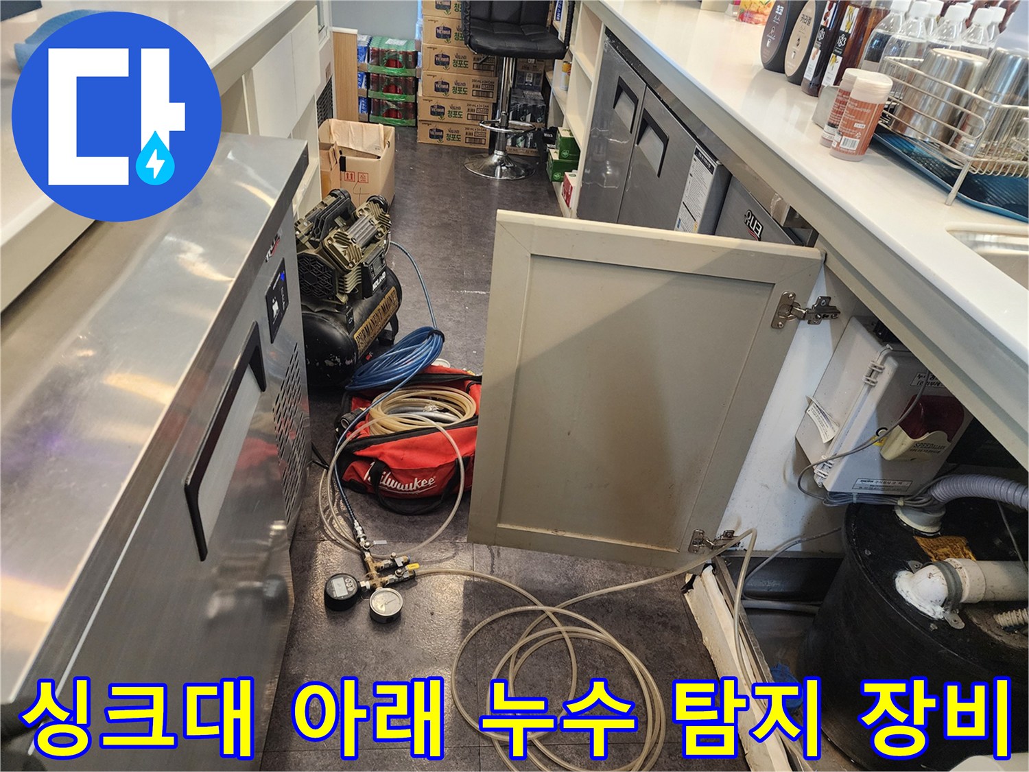 복잡한 주방 배관 사이에서 작동 중인 누수 탐지용 압력계와 튜브