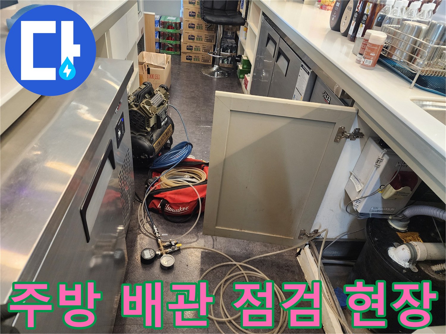 상업용 주방 싱크대 하부의 복잡한 배관과 탐지 장비 모습