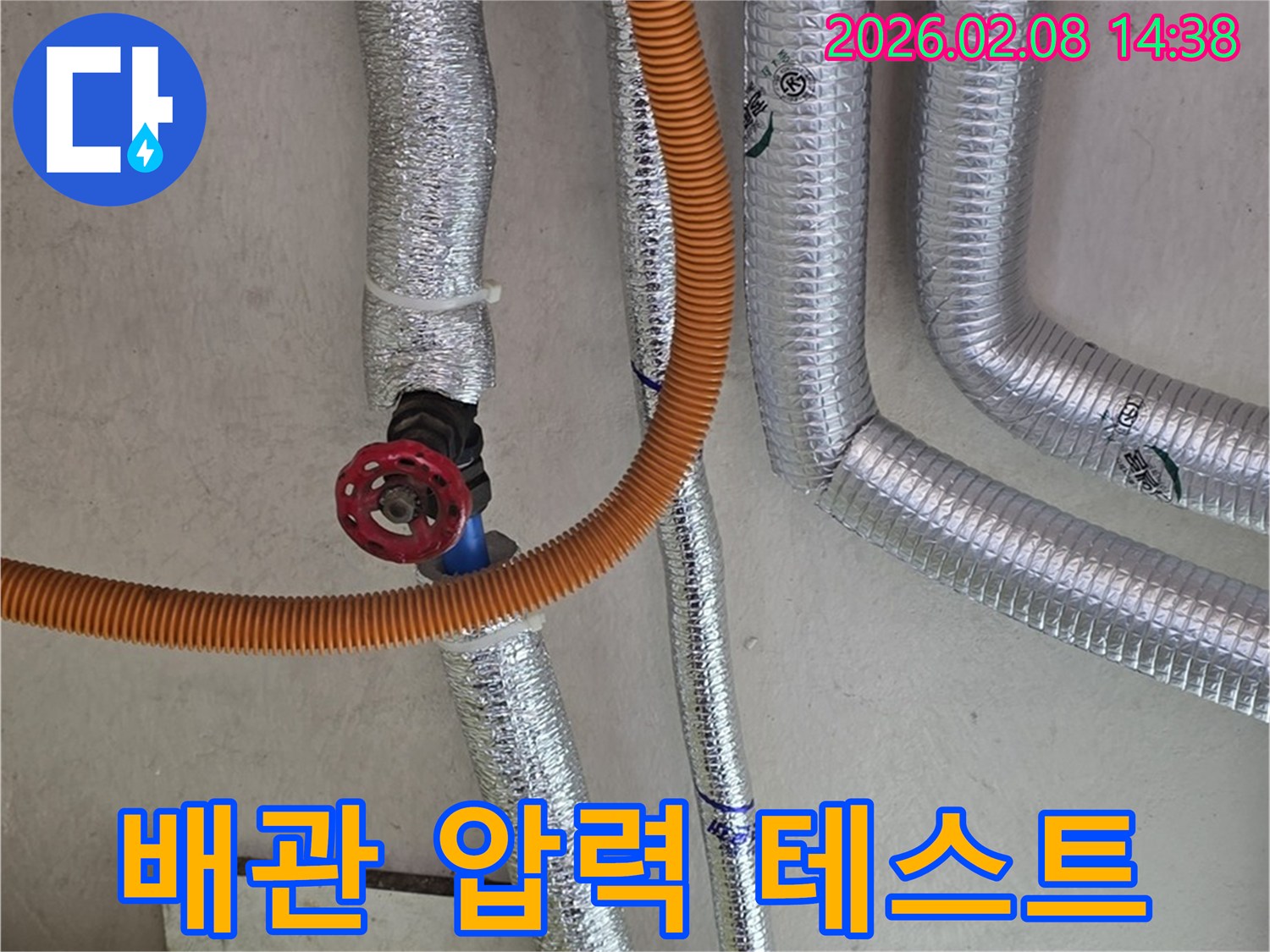 누수-탐지 현장에서-단열된-배관에-주황색-호스를-연결하여-압력-테스트를-진행하는-모습