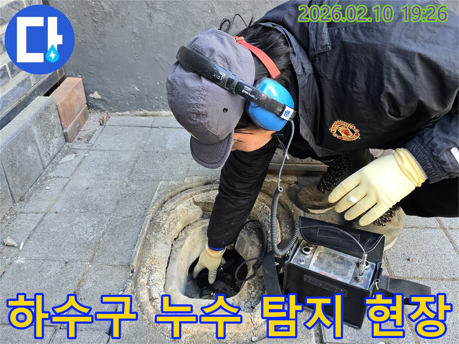 전문가가 특수 청음 장비를 활용하여 지하 하수관의 누수 여부를 면밀히 확인하고 있는 장면입니다.