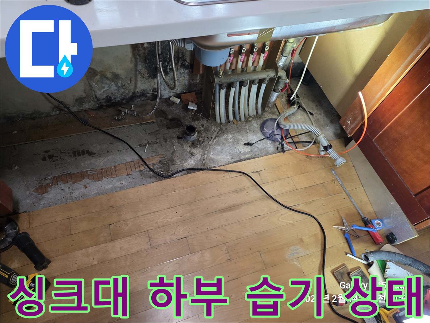 싱크대 아래 배관 주변의 젖은 바닥과 곰팡이 발생 부위