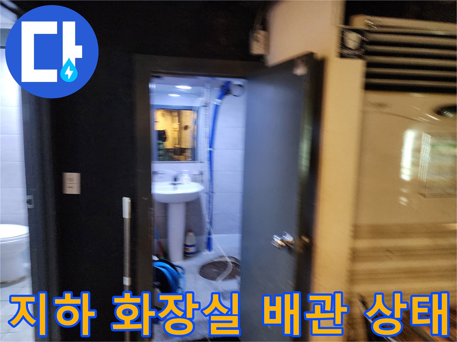 지하층 화장실의 노출된 파란색 주름관과 세면대 하부 배관 모습