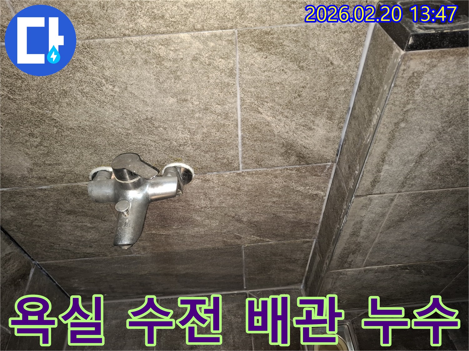 욕실 벽면에 설치된 수전의 배관 연결 부위를-누수 여부를 확인하기 위해-정밀하게 검사하는 장면