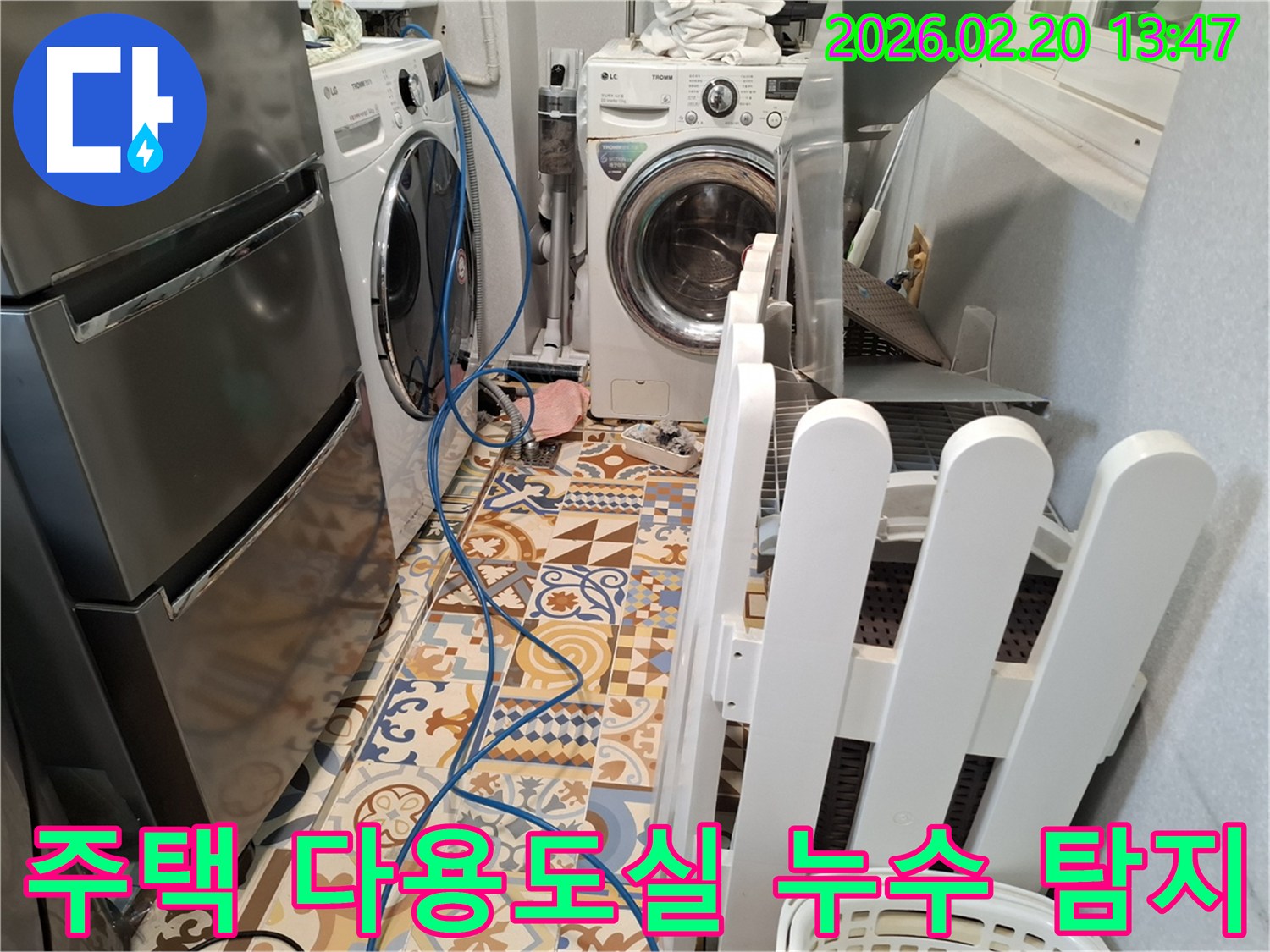 주택 다용도실 바닥에 누수 탐지 장비 호스가 연결된 채-세탁기와 냉장고가 보이는 현장입니다.