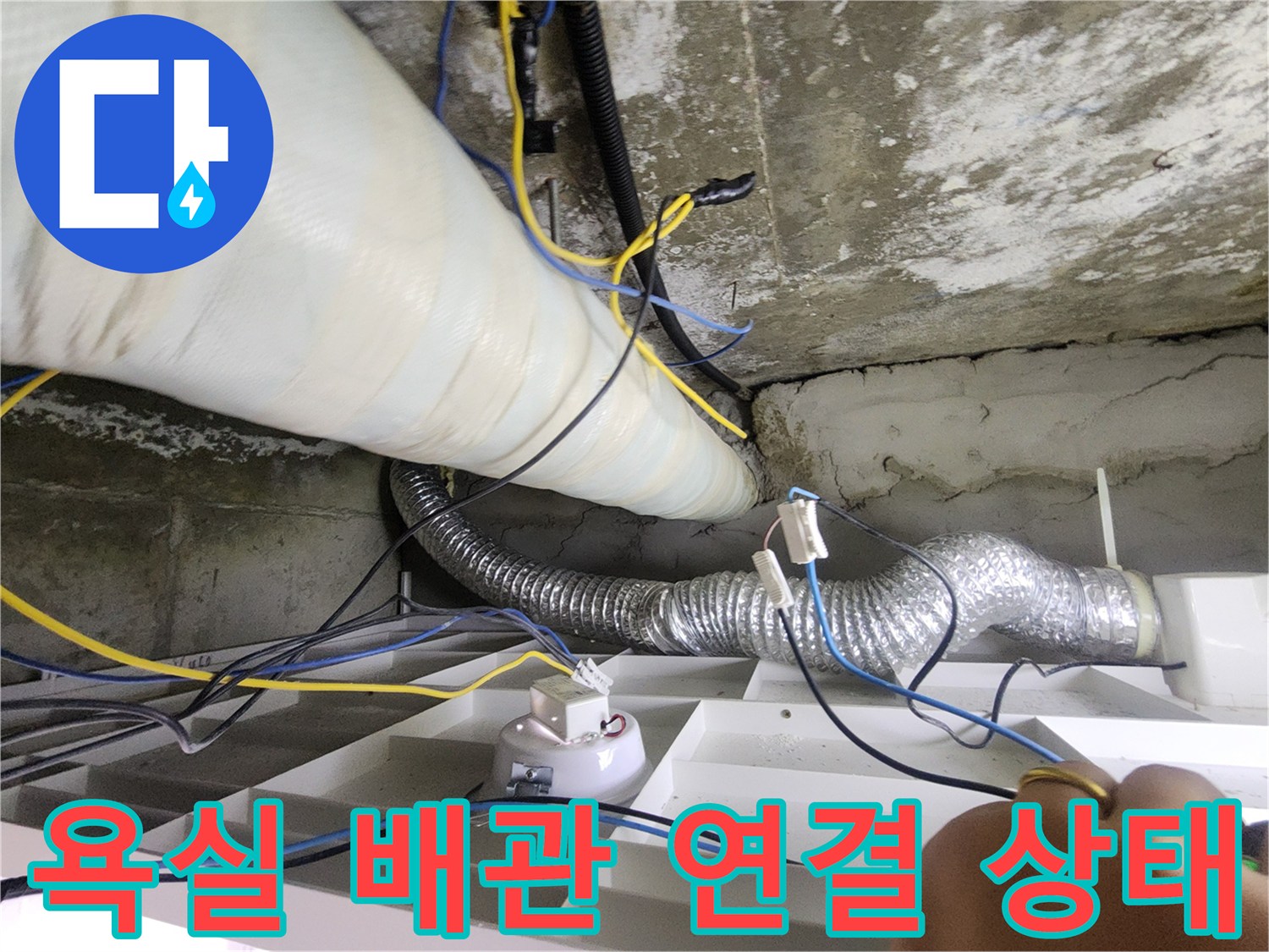 화장실 천장 구조물 사이로 보이는 은색 주름관과 전선들