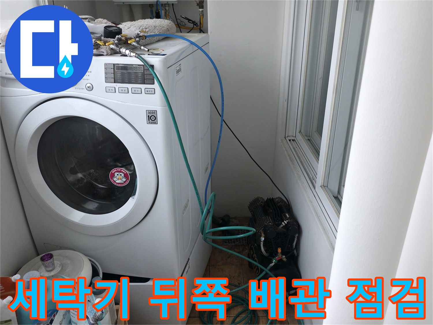 세탁기 윗부분의 수도 부속에 압력 측정용 장비가 연결된 장면입니다.