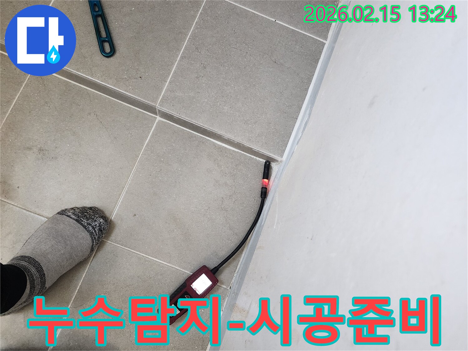 누수 엔지니어가 바닥 타일과 벽면 경계에서 누수탐지기를 사용하여 공사 전 정밀 진단을 하는 모습