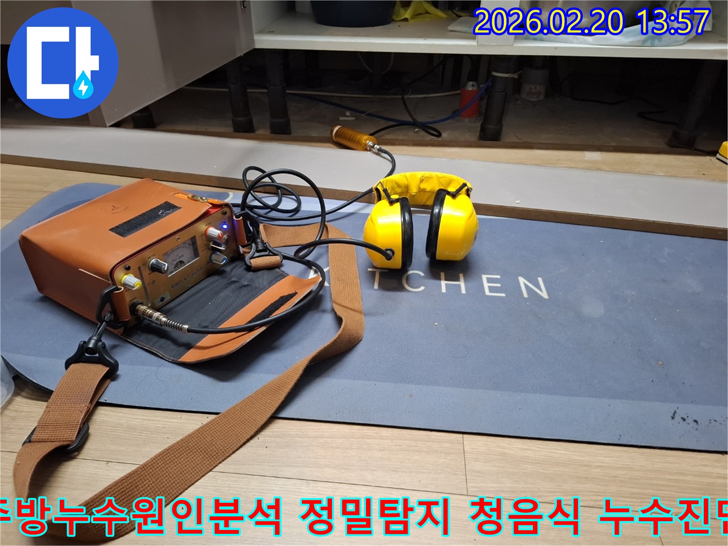 누수 엔지니어가 주방의 숨겨진 배관 누수를 찾아내기 위해-첨단 청음식 탐지 장비를 활용하는 모습입니다-헤드폰으로 미세한 누수음을 감지합니다