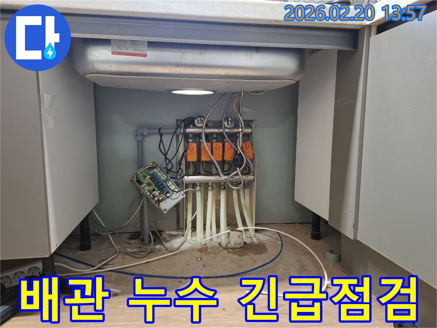싱크대 하부의 복잡한 배관에서-누수가 발생하여-전문 엔지니어가 긴급하게 점검하고-원인을 파악하고 있습니다