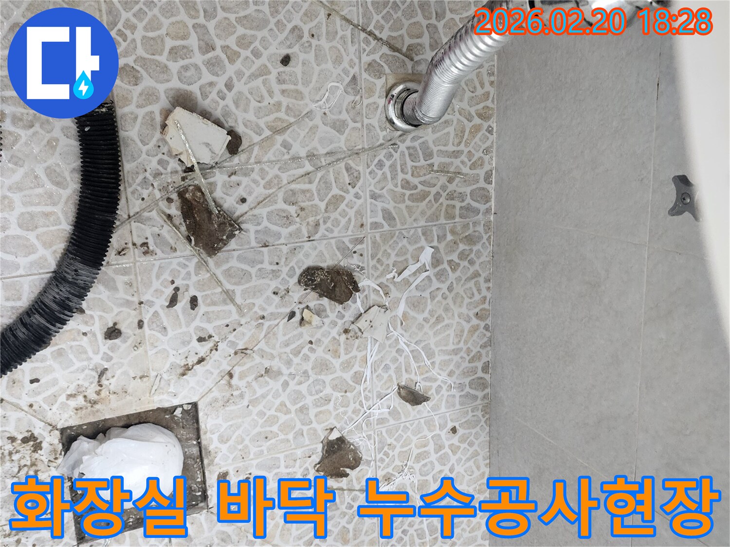 이 이미지는 동대문구 주택의 화장실 바닥 누수 공사 현장을 보여주며-오래된 배관 문제로 인한 물샘을 해결하기 위해-전문 엔지니어가 바닥을 파쇄한 모습입니다.