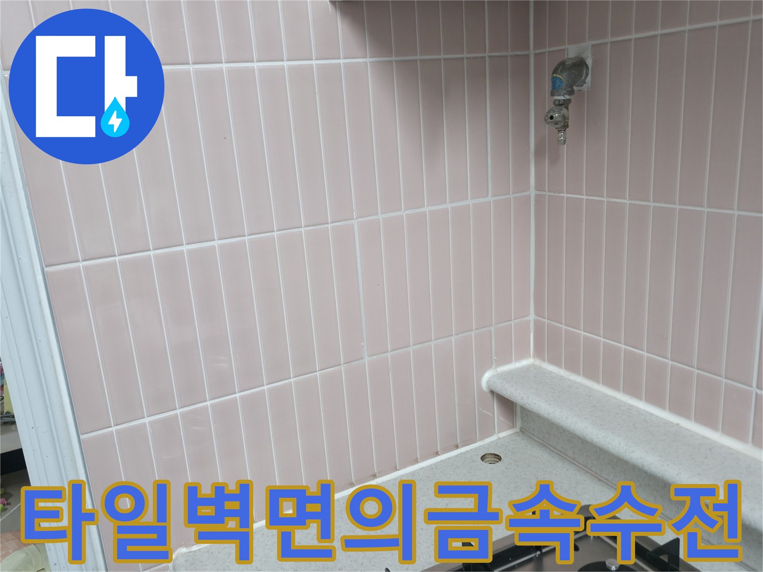 분홍색 세로 타일 벽에 설치된 수도꼭지와 싱크대 상판 끝부분