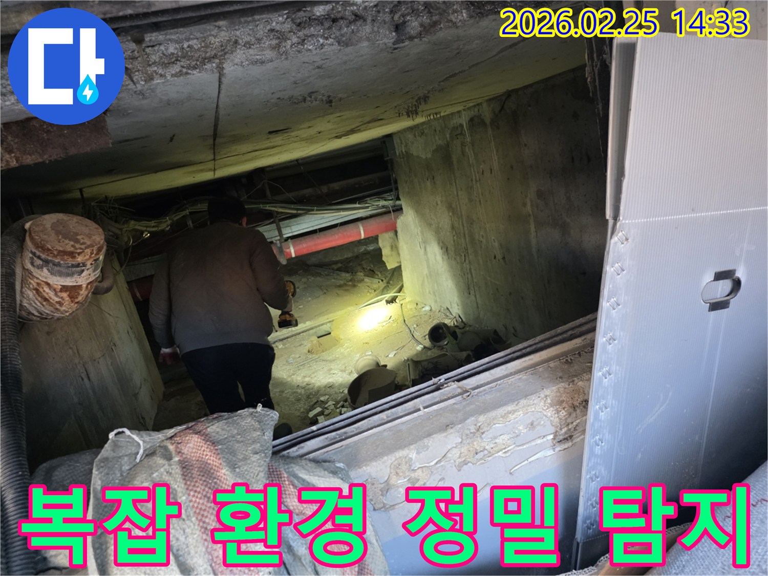 누수 전문 엔지니어가-어둡고 복잡한 환경 속에서-손전등을 비춰가며-수많은 장애물 사이로-누수 지점을 정밀하게-탐지하는 모습입니다.