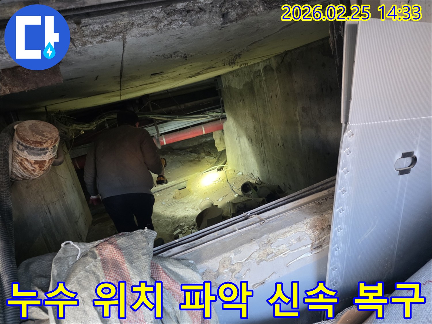 누수 전문 엔지니어가-어둡고 좁은 공간에서-손전등을 비춰가며-누수 발생의 정확한 위치를-탐지하기 위해-집중하는 모습입니다.
