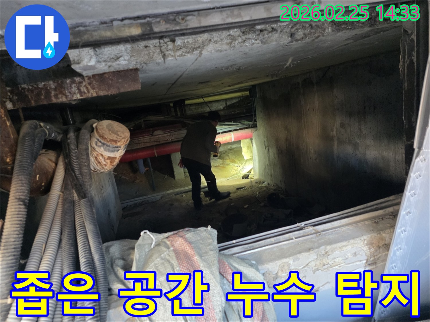누수 전문가가-손전등을 비추며-배관이 복잡한-지하 통로를-조사하는 모습